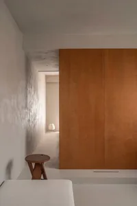 A minimalist interior space with a wooden wall and concrete flooring.