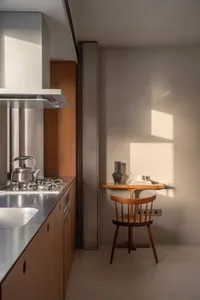 A minimalist kitchen with refined materials, featuring a sleek stainless steel countertop and cabinets with clean lines.