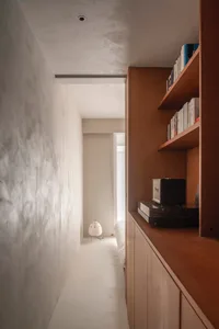 A minimalist bedroom with a wooden shelf, books, and a small table lamp.