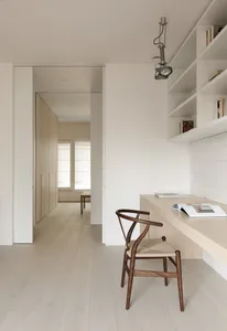 Modern minimalist home office featuring a wooden desk, metal chair, and open shelving.