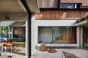 Modern residential interior featuring concrete walls and floors, large windows, and minimalist furniture.