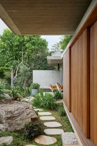 Concrete and wooden exterior of a modern residential home with a walkway leading through the garden.