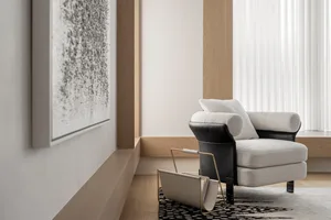 A minimalist living room with a fabric armchair and wooden flooring.
