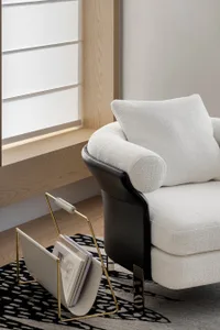 Modern minimalist living room featuring a textured white textile sofa with black accents and a sleek metal magazine rack.