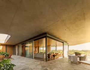 A modern living room with concrete walls and glass windows.