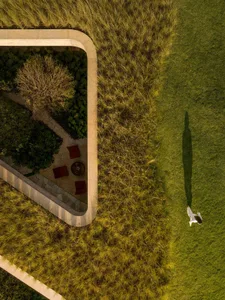 Aerial view of a modern landscape design featuring a green grass lawn bordered by concrete pathways and a small garden area w