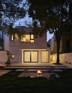 A modern house exterior with a fire pit in a backyard