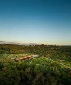 Modern residential house with a green rooftop and concrete exterior nestled among trees and bushes.