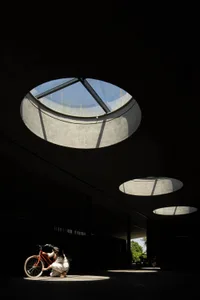 A modern interior space featuring a concrete ceiling with circular openings allowing natural light to filter in.