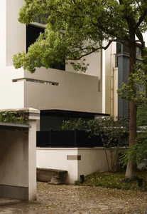 Modern minimalist building with concrete exterior and greenery.
