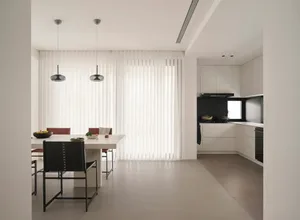 A modern, minimalist kitchen with a sleek white countertop and black pendant lights hanging above a dining table.