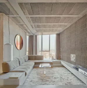 A minimalist living room with concrete walls, large windows, and a comfortable seating area.