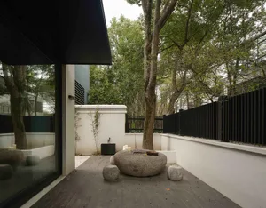 A minimalist terrace garden featuring stone elements and a large stone table with stools.
