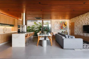 Modern kitchen with concrete floor, wooden cabinets, and stone walls.