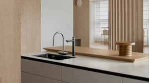 Modern kitchen featuring a sink with a black basin and a wooden stool on the countertop.