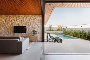 A modern patio with concrete flooring, glass walls, and outdoor furniture.