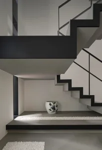Modern concrete staircase with black metal railings and white ceramic pot.