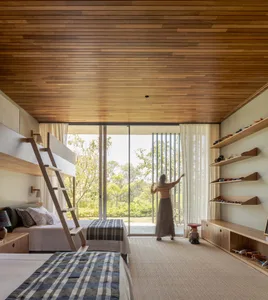 A modern bedroom with wooden furniture and a large window overlooking a green landscape.
