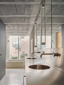 Modern minimalist bathroom featuring concrete countertop with sinks and metallic fixtures.