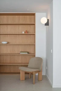 Minimalist reading corner featuring wooden shelves with a few books and decorative items.