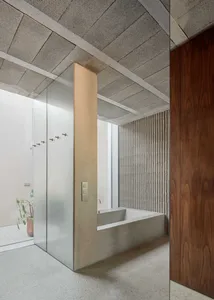 A modern bathroom featuring a concrete bathtub, glass shower enclosure, and wooden accents.
