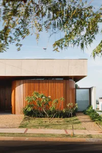 A modern home with a concrete and wood exterior, featuring a circular section and a glass window.