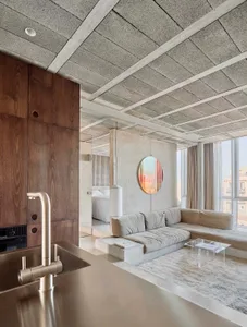 Modern living room featuring a concrete ceiling, wooden cabinets, and a comfortable sectional couch.