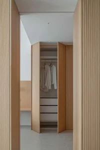 Modern-style walk-in closet with wooden hanging rails and minimalist design, featuring a white ceiling and grey floor tiles.