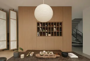A modern study room featuring wooden elements, a large spherical light fixture, and a table with various items.
