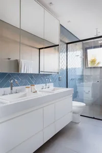 Modern bathroom with blue herringbone tile flooring and white cabinetry.