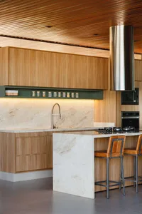 A modern kitchen interior featuring wooden cabinets and marble countertops.