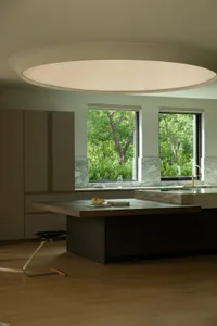 A well-lit residential kitchen features a large island with a wooden countertop and a marble backsplash, surrounded by minima
