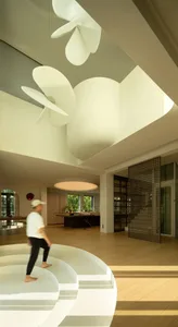 A modern interior space featuring a circular white concrete staircase.