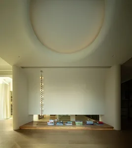 A minimalist living room with a wooden floor and a modern light fixture.