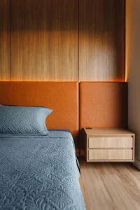 A modern bedroom featuring wooden furniture and a blue quilted bedspread.