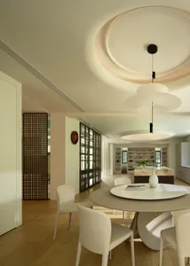 A modern dining room featuring metal and plastic materials with a round table and chairs, a central pendant light, and a book