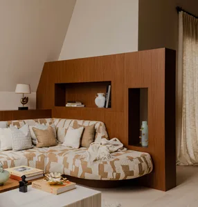 A modern interior living room with a wooden panel wall featuring built-in shelves and a patterned sofa.