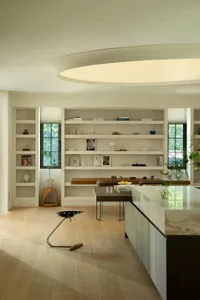 A modern living room with wooden flooring, concrete walls, and marble countertops and shelves.