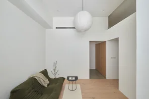 Modern living room featuring a wooden floor, minimalist furniture, and soft lighting.