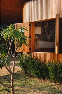 Modern residential facade with wooden slat exterior and greenery around.