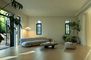 A modern residential kitchen with white walls and hardwood floors, featuring minimalist design and sleek appliances.