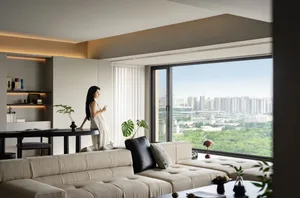 Modern living room with neutral-toned furniture and minimalist decor, featuring a large window with a cityscape view.