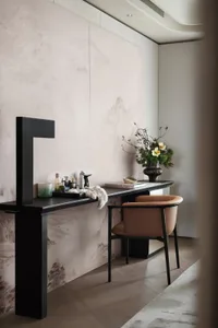 A modern workspace featuring a minimalist desk with a leather chair and a calm, neutral color palette, with a vase containing