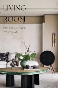 A modern living room featuring metallic furniture and a round glass-top coffee table with a vase of white orchids and greener