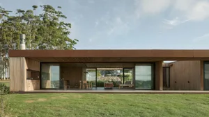 Modern house exterior featuring a flat roof and large windows, constructed with wood.