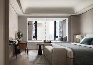 Modern minimalist bedroom featuring a large bed with neutral textiles, a sleek desk, and a comfortable seating area by the wi