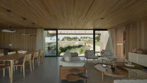 Modern minimalist living room with wooden coffee tables, leather sofa, and sliding glass doors leading to an outdoor area.