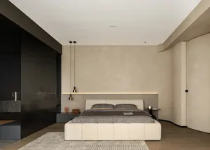 A modern bedroom featuring a minimalist white bed with a beige headboard and a neutral-toned rug on hardwood floors.