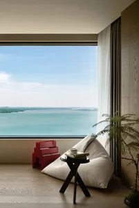 Contemporary living room featuring a modern sofa, floor-to-ceiling windows with blinds, and a view of water.