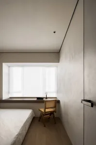 A minimalist bedroom with a bed, chair, and window.